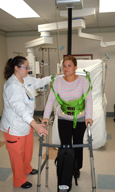 A nurse is using a ceiling lift to support a patient walking A nurse is using a ceiling lift to support a patient walking